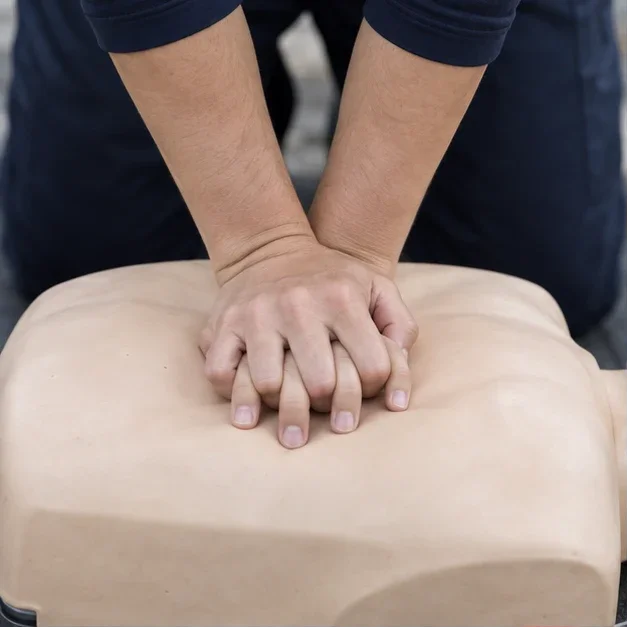 Illustrative close-up of hands practicing chest compressions on a training manikin